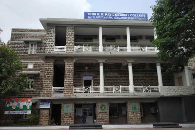 Stone-faced Shri B M Patil Medical College building in Vijayapura with the college name board above the entrance
