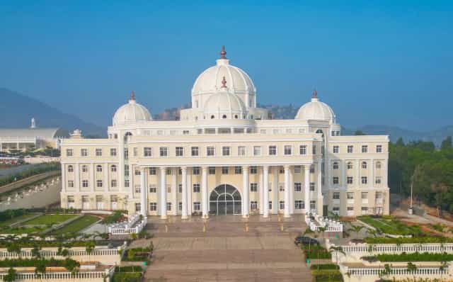 Front aerial view of the domed main academic building of Sri Madhusudan Sai Institute of Medical Sciences and Research at Sathya Sai Grama, Muddenahalli, Chikkaballapur