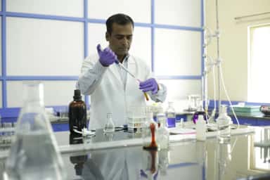Faculty member pipetting reagents in a biochemistry laboratory at AIMS