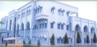 Arched campus block of Al-Ameen Medical College with a college bus in front