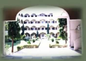 Al-Ameen Medical College campus building and gardens seen through the entrance arch