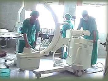 Staff position a mobile C-arm imaging unit in the operation-theatre block at Al-Ameen Medical College Hospital