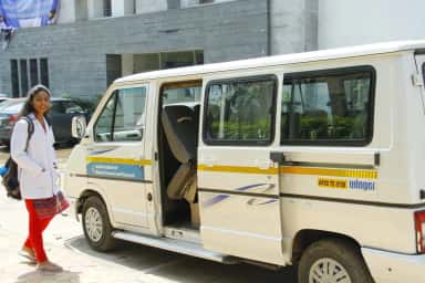 MBBS student in a white coat beside the Apollo Institute of Medical Sciences and Research college vehicle on campus