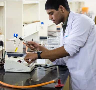 Student in an Apollo Institute of Medical Sciences and Research lab coat working at a laboratory bench