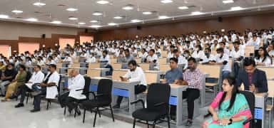 MBBS students in white coats filling a large lecture theatre at Banas Medical College & Research Institute, Palanpur