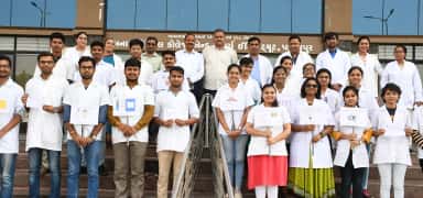 Banas Medical College & Research Institute MBBS students in white coats on the college steps below the college name banner