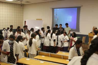 Medical students in white coats interacting in a seminar hall at Bhaskar Medical College