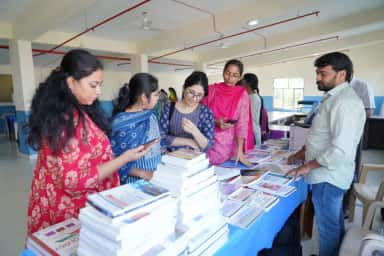Students browsing medical textbooks at a book exhibition during a CMR Institute of Medical Sciences academic event