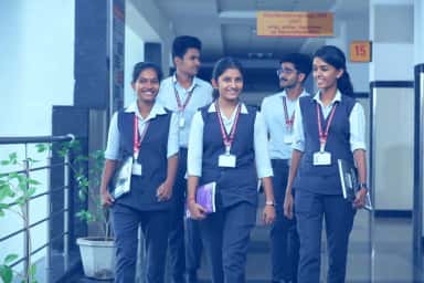Students of Dhanalakshmi Srinivasan Medical College in uniform with ID lanyards walking through a campus corridor