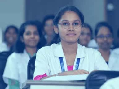 MBBS student in a white coat seated in a classroom at Dhanalakshmi Srinivasan Medical College, Perambalur