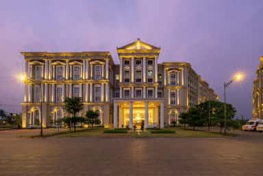 Main entrance portico of CDSIMER at dusk with ambulances, Harohalli
