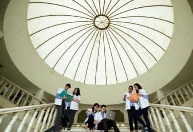 MBBS students in white coats on the staircase under the central dome of Dr. D. Y. Patil Medical College, Pimpri