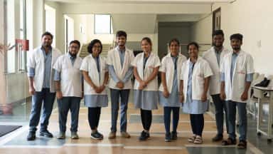 MBBS students of Dr. Patnam Mahender Reddy Institute of Medical Sciences in white coats inside the college building