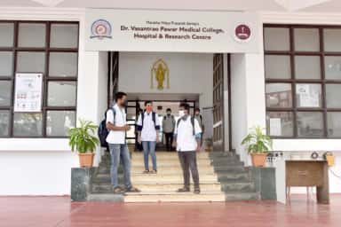 Students in white coats at the entrance steps of Dr. Vasantrao Pawar Medical College, Nashik
