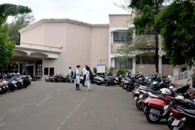Academic block and two-wheeler parking with students at Dr. Vasantrao Pawar Medical College, Nashik