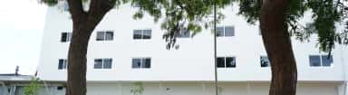 White campus block of Farookh Academy of Medical Education seen through trees