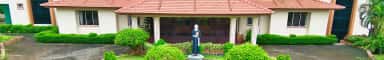Statue of founder Fr Augustus Muller in front of a tiled-roof building on the Father Muller campus, Kankanady