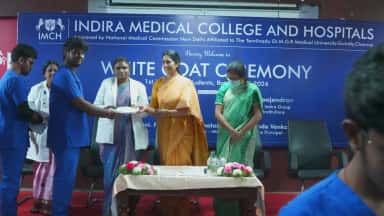 Indira Medical College & Hospitals White Coat Ceremony on a branded stage marking an MBBS cohort, Thiruvallur