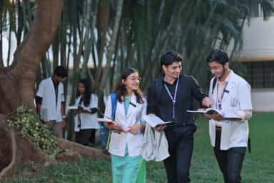 Medical students walking through the tree-lined KAHER JNMC campus in Belagavi