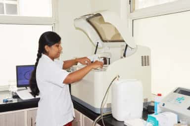 Technician loading samples into an automated analyser in the pathology lab at Jawaharlal Nehru Medical College Belagavi
