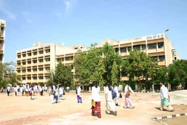Students walking across the JJM Medical College campus in front of the Kavery hostel building
