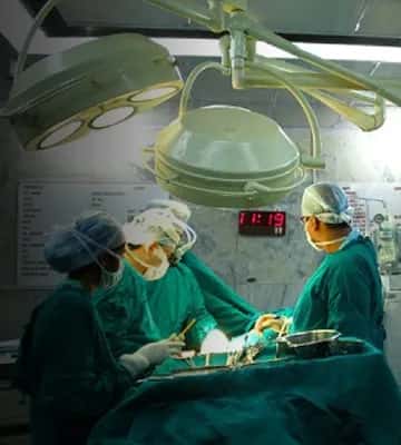 Surgeons at work under theatre lights in a KMC Mangalore teaching hospital operating room