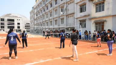 Students playing volleyball on the campus court beside the college buildings at Malla Reddy Institute of Medical Sciences
