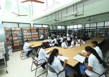MBBS students reading at tables among bookshelves in the central library at MAPIMS Melmaruvathur