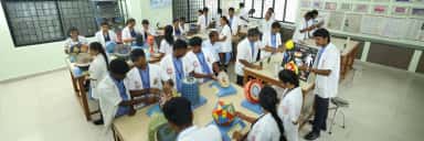 MAPIMS students in white coats studying anatomical and pathology models in a museum laboratory with wall charts