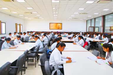 Large study and reading hall full of MBBS students at MGM Medical College, Aurangabad, beneath a portrait of Mahatma Gandhi
