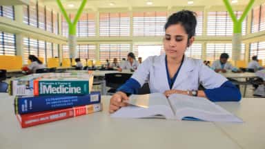 Student reading medical textbooks in the Navodaya Medical College library reading hall