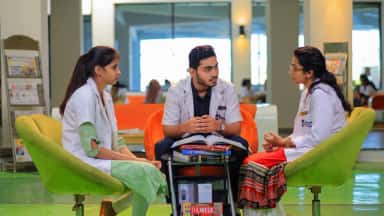 Medical students in white coats discussing over textbooks in the Navodaya library lounge