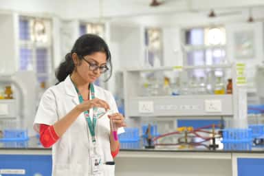 Student handling a test tube in the biochemistry laboratory at Neelima Institute of Medical Sciences
