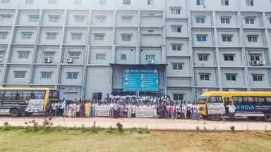 NIMSRC Hospital building with students and Nova college buses assembled in front, Jafferguda campus