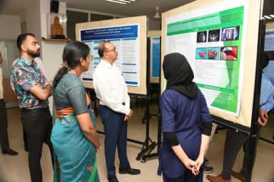 Faculty and residents reviewing scientific posters at SDM College of Medical Sciences and Hospital, Dharwad