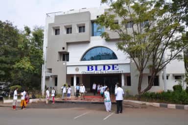 BLDE Deemed to be University administrative building with medical students in white coats outside