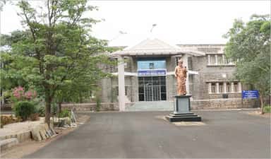 Original stone building of Shri B M Patil Medical College with the founder's statue in front