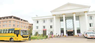 Outpatient block and college buildings of Sri Chamundeshwari Medical College Hospital and Research Institute, Channapatna, with a branded college bus in front