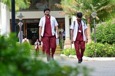 MBBS students in scrubs and white coats walking out of the academic block at Sri Devaraj Urs Medical College
