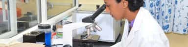 Laboratory technologist using a microscope in a clinical laboratory at Srinivas Hospital, Mukka