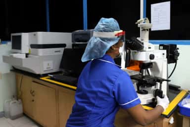Laboratory technician at a microscope in the central clinical laboratory of SRM Medical College Hospital