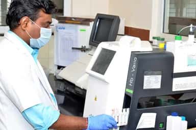 Technician operating a haematology analyser in the clinical laboratory at S S Institute of Medical Sciences, Davangere
