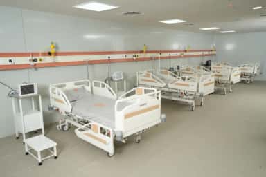 Row of hospital beds with bedside monitors and central oxygen panels in a ward at Takshashila Medical College Hospital