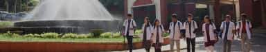 Fountain courtyard and academic block with students in white coats at Yenepoya Medical College, Mangalore