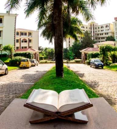 Open Quran monument in a garden courtyard with Yenepoya campus buildings behind at Deralakatte, Mangalore