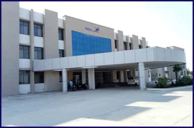 Blue-glass facade and covered portico of the Zydus Medical College and Hospital teaching block at Dahod