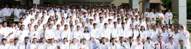 Large group of Zydus Medical College and Hospital students and faculty in white coats outside the college, Dahod