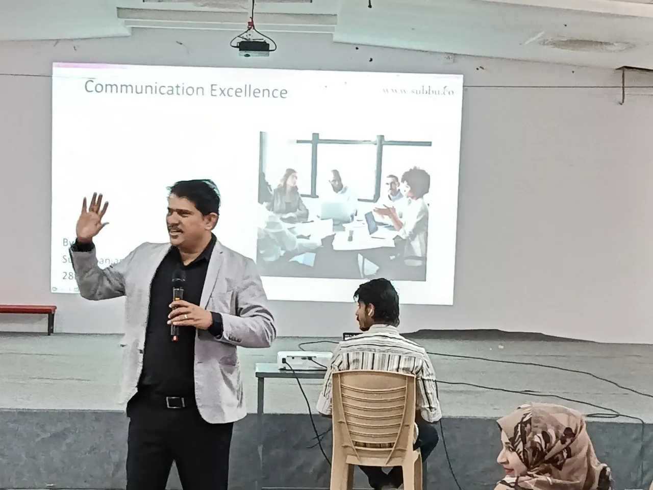 Man giving a presentation on communication excellence with audience members. — sjes-college-of-management-studies-bengaluru