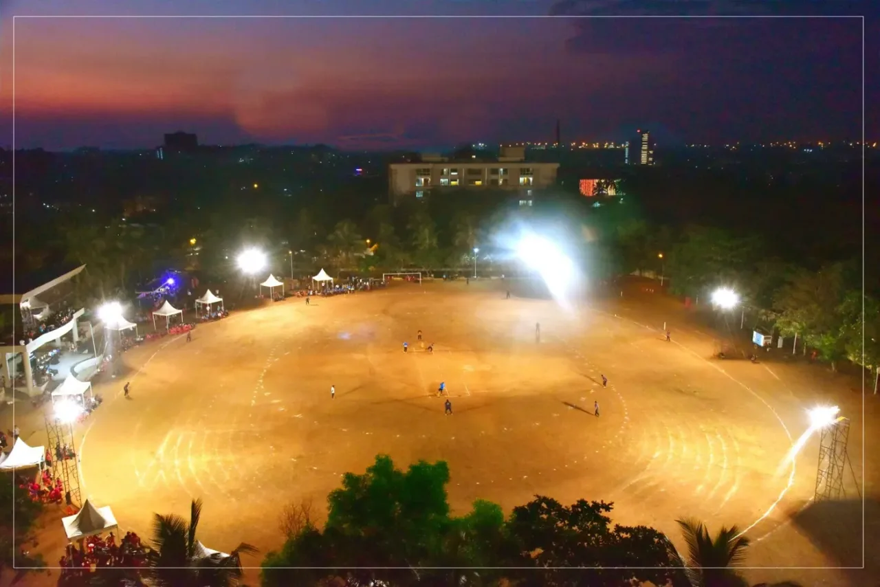 Floodlit sports ground at dusk on the AJIMS campus, Mangalore