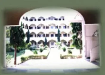 Al-Ameen Medical College campus building and gardens seen through the entrance arch